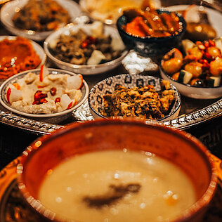 Levantine Platte mit mehreren kleinen Schalen voller warm‑kalter Mezze, Eintöpfen und Dips auf verziertem Metalltablett.
