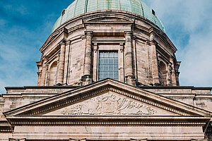 Neoklassizistisches Gebäude der Deutschordenskommende am Jakobsmarkt mit großem grünen Kuppeldach, Säulenportal und verziertem Giebelrelief.