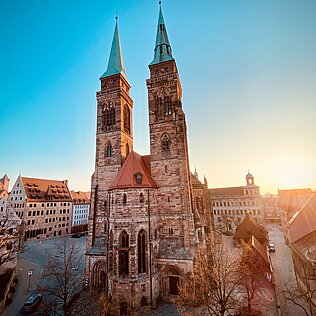 Die Sebalduskirche in Nürnberg mit zwei hohen Türmen bei Sonnenaufgang und klarem Himmel